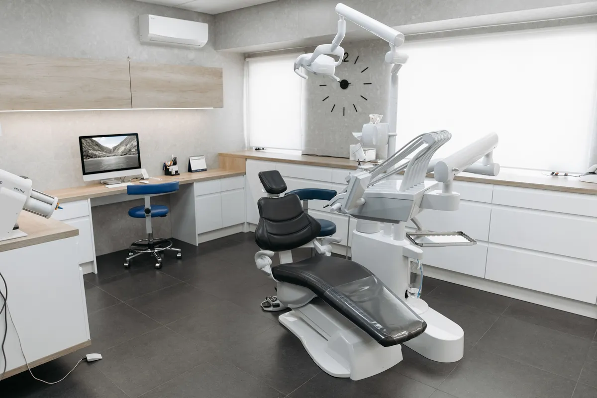 A bright treatment room with one dental chair beside a wide window