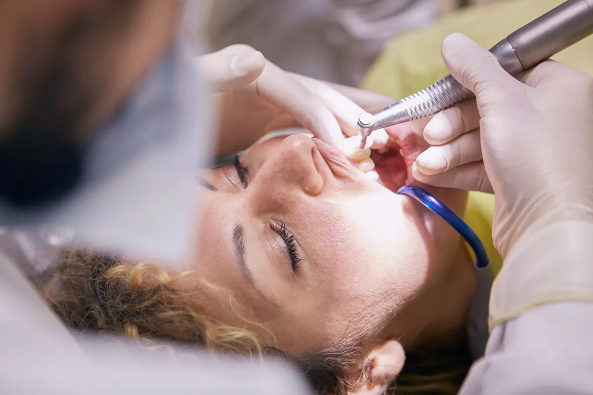 The dentist repairing a patient's tooth with a small dental drill