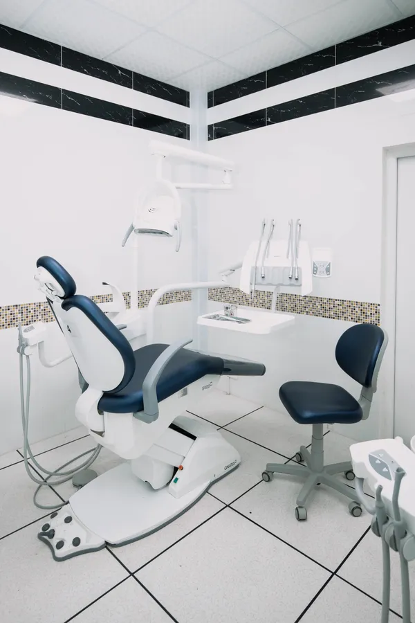 An empty treatment room with a blue dental chair ready for the next patient