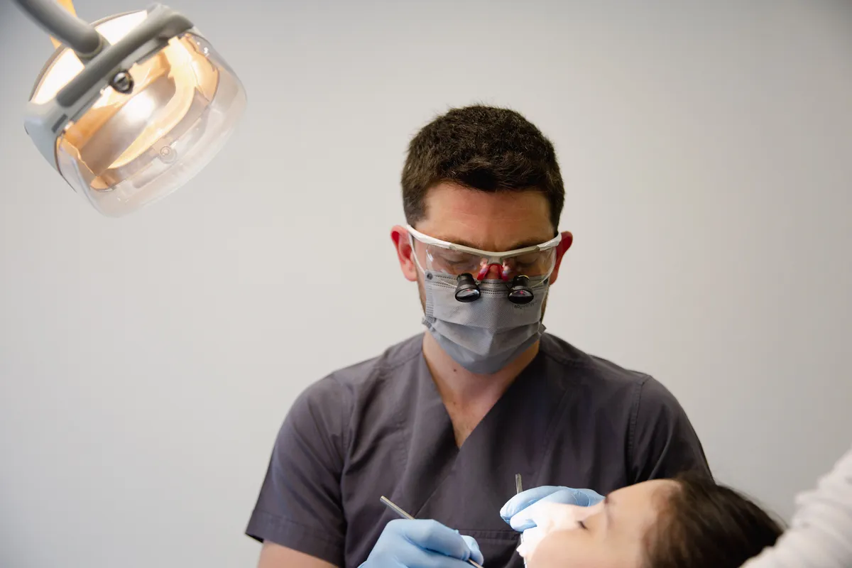 Dr. Daniel Nair working at the chair with loupes and a mask